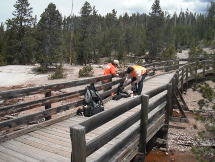 USGS scientists installing a temperature sensor under a public boardwalk in Norris Geyser Basin, Yellowstone National Park ca. 2010