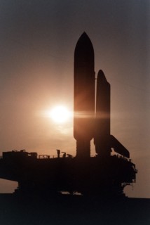 Cast in silhouette by the rising sun, the Space Shuttle Atlantis slowly and carefully makes the journey along the Crawlerway between the Vehicle Assembly Building and Launch Pad 39A ca. 1997