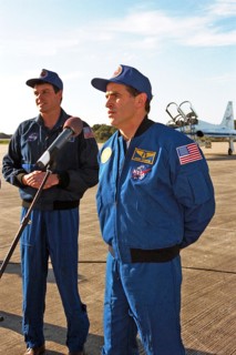 As STS-87 Commander Kevin Kregel looks on, Payload Specialist Leonid Kadenyuk of the National Space Agency of Ukraine addresses members of the press and media ca. 1997