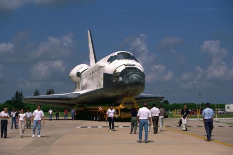 Space Shuttle Orbiter Discovery rolls over from Orbiter Processing Facility 2 on top of the orbiter transporter to the Vehicle Assembly Building for mating with its external tank and solid rocket boos...