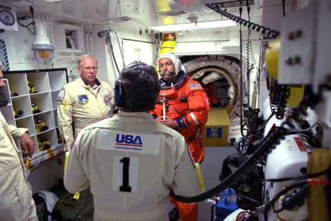 STS-84 Mission Specialist Carlos I. Noriega prepares to enter the Space Shuttle Atlantis at Launch Pad 39A with help from white room closeout crew members ca. 1997