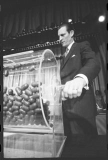 Curtis W. Tarr, director of the Selective Service System, turns the drum containing capsules of draft numbers at the annual draft lottery. Washington, DC, 2/2/1972. Thomas O' Halloran, photographer.