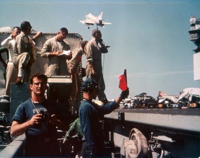 Landing Officer waves off an A-4 Skyhawk while crew prepares to receive another aboard USS ENTERPRISE. 6/65.