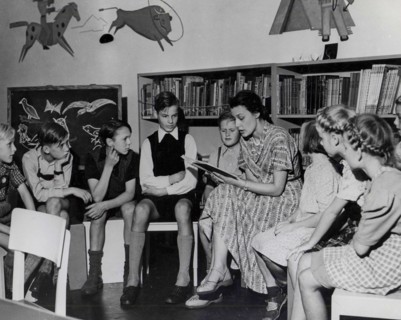 Employee reads stories to a group of youngsters in the children's day room of the Amerika Haus, Hamburg.