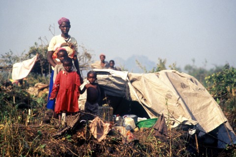 1994 - A Rwandan family pose in front of their makeshift home