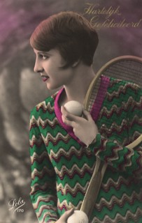 Woman with short hair & sweater with tennis racquet and ball.