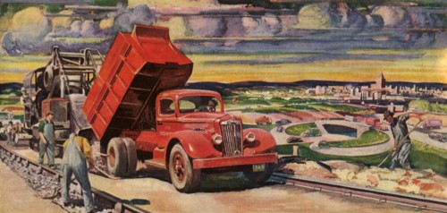On outskirts of town a truck pours cement for road workers.
