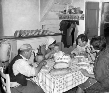 famille à table à l'arrière de la boulangerie, miches de pain toscan sur la table, 1967