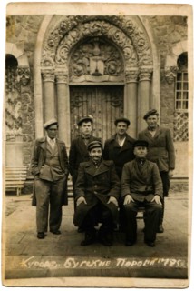 Group of men posing against the backdrop of a historic building.