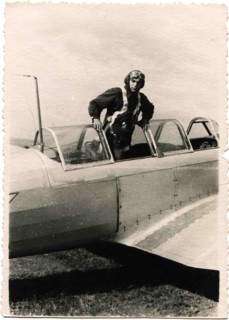 Pilot in a helmet standing in front of the cockpit of military aircraft.