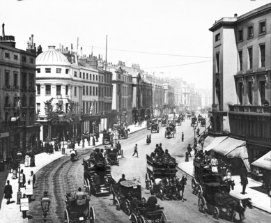 Regent Street with horses and carriages and lots of people in the street.