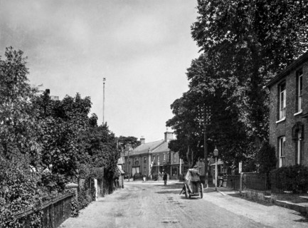 Wretham in Suffolk a typical street with a man on a cart and a man on a bicycle.