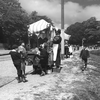 A view of children and people at a market in the park, perhaps an exhibition.