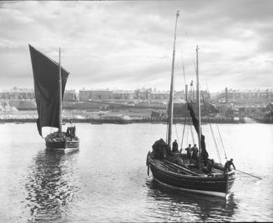 Fishing boats leaving harbour with South Shields town in the background.