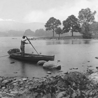 A man punting a rowing boat on Lake Windermere.