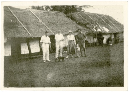 Dorothy Tamlin outside thatched houses