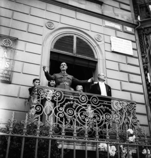 General Charles de Gaulle on a balcony waving to the crowd in Geneva, 1946 .