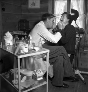 Dentist with patient, in the 40s .