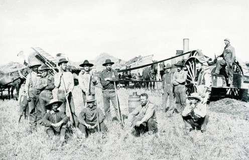 This 1903 picture of the Threshing Crew has a large machine at the right that is the engine for