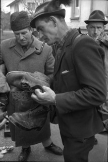 Thun, selling of disused army equipment, man examining shoes; 1969.