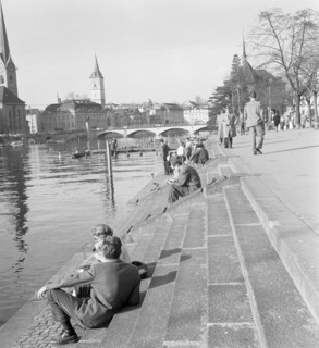 People strolling along the Limmat river.