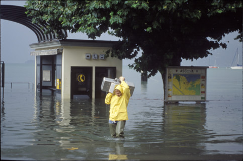 Man carrying a coin-box telephone, flood in Ascona 1993
