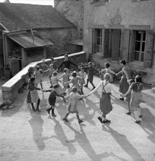 Coinsins; Teacher Elisabeth Glauser and her class playing ringaringaroses; 1949