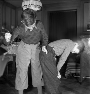 Boy mending his brother's trousers on Mother's Day, 1941.