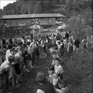 Children helping to displace an old wooden bridge; 1952.