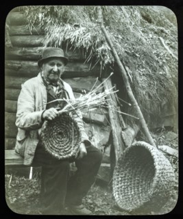 Portrait of elderly countryman weaving straw baskets in England, c 1890s-1900.