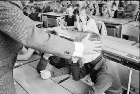 Teacher and pupils playing scene of corporal punishment, 1969,