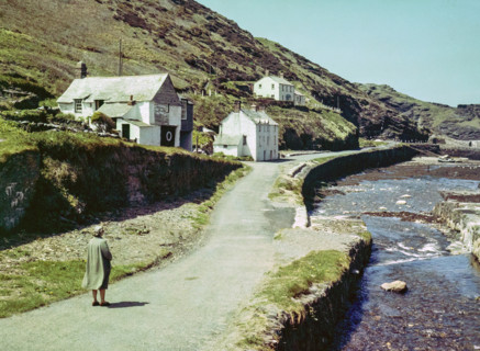 Road passing historic buildings by harbour wall fishing village of Boscastle.