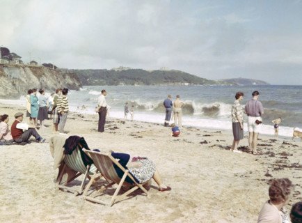 People on sandy beach looking at breaking waves.