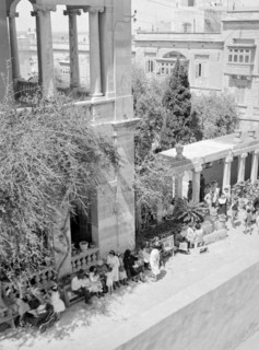 Nun with children in garden of classical buildings presumably a primary school.