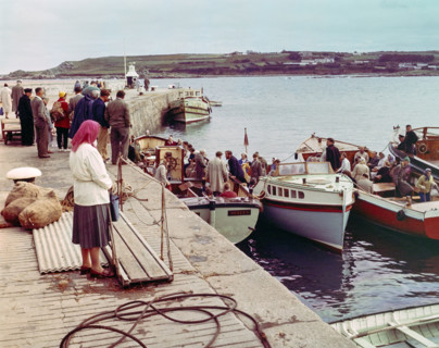 People boarding tour boats from the quayside in the harbour at Hugh Town.