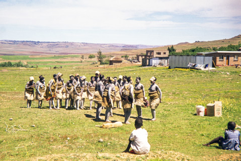 Basotho women dancers in traditional attire practice a performance in a rural area.