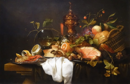 Still life with a basket of fruit, a gilded goblet, a rumer glass, ham, pie, crab and lemon on a table.