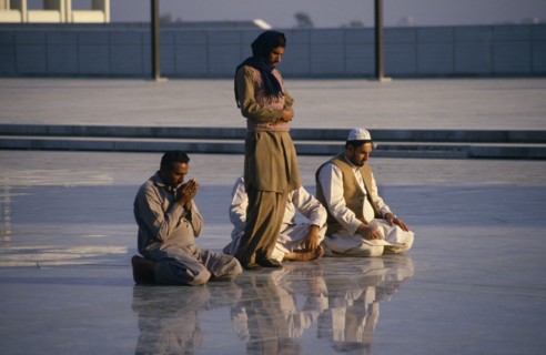 PAKISTAN, Islamabad, "Faisal Mosque. Four men at prayer, reflected in surface of  shiny marble