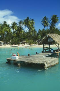 WEST INDIES, Tobago, Pigeon Point, Boat jetty with tourist sitting down and the beach behind with