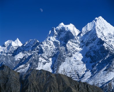 NEPAL, Sagarmatha National Park, Himalayan mountain peaks with moon above just visible in deep blue