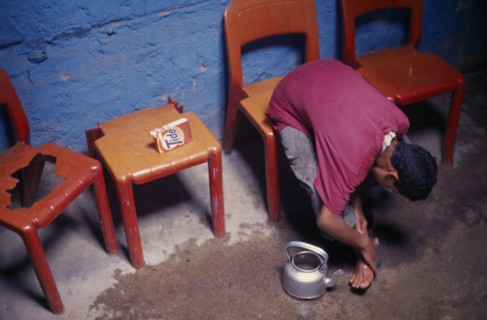 MOROCCO, General, Boy sitting on a chair washing his feet