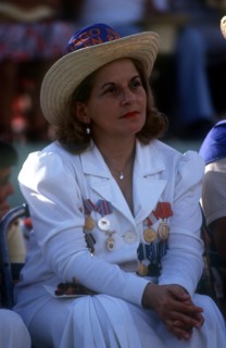 CUBA, Santiago, Seated woman dressed in white with medals pinned to the front of her jacket