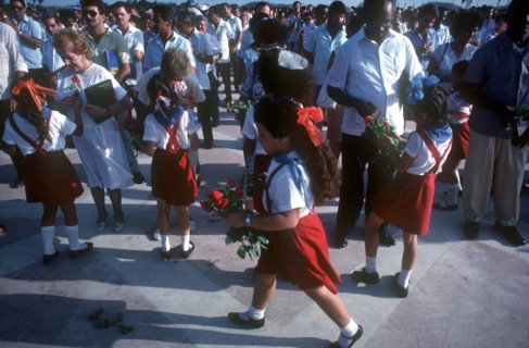 CUBA, Santa Clara, School children wearing red and white uniforms distributing red roses to adults