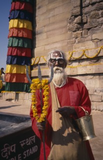 INDIA, Uttar Pradesh, Sarnath, Sadhu holding a trident standing by a stupa
