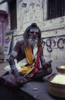 INDIA, Uttar Pradesh, Varanasi, Sadhu sitting cross legged with a bugle in his lap