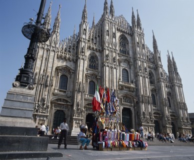 ITALY, Lombardy, Milan, Cathedral frontage with tourists  beside a souvenir stall selling flags and