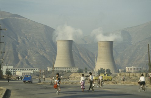 CHINA, Gansu Province, Lanzhou, Coal Power Station with people walking in the foreground.