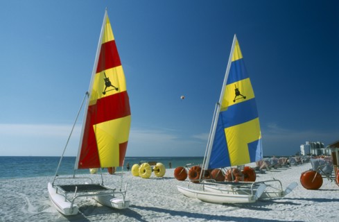 USA, Florida  , St.Petersburg, "Hobbie Cats with bright blue, red and yellow sails pulled up onto