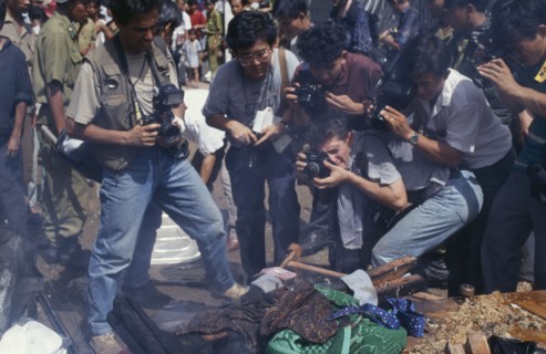 CAMBODIA, Phnom Penh, Press photographers taking close up photographs of a bonfire of the looted