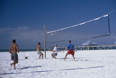 USA, Florida, Clearwater , People playing beach volleyball with small pier in the background